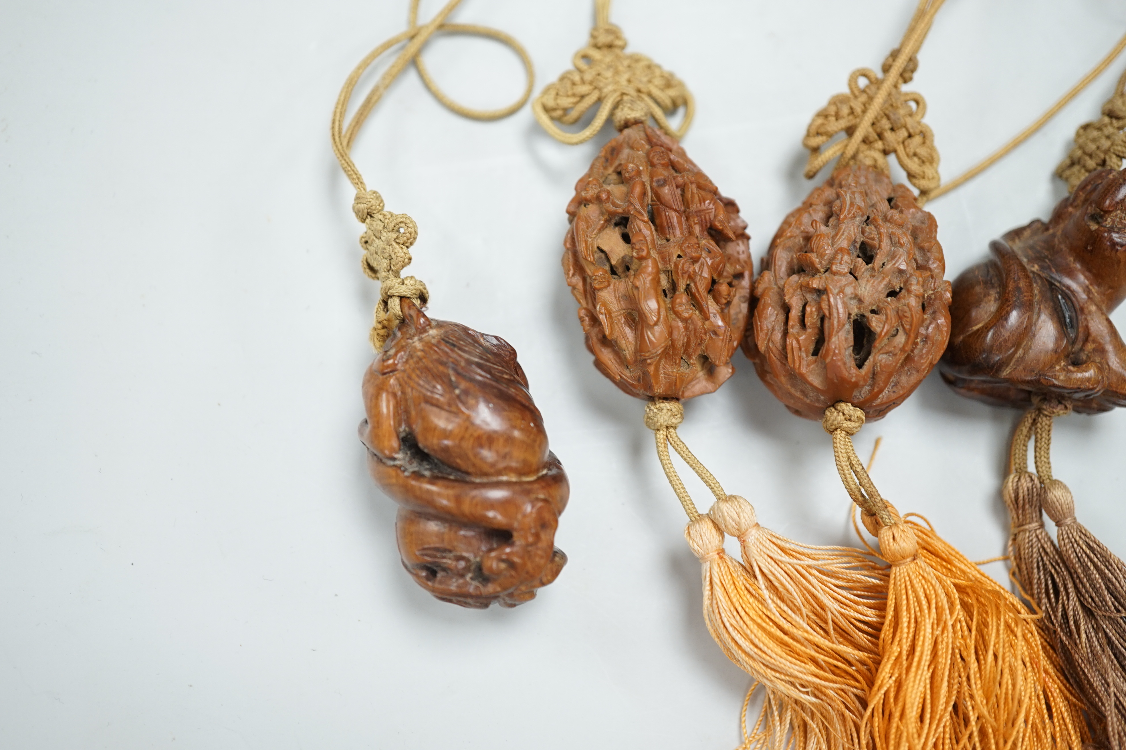 Two Chinese peach stone carvings and two carved wood toggles on a silk cord